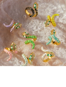 Detailed display of assorted colorful enamel snake rings on textured glass surface
