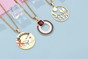 Detailed close-up of three gold titanium necklaces with enamel pendants and red gems