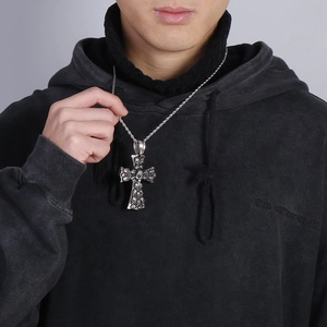 Close-up of gothic stainless steel cross necklace featuring detailed skull relief texture