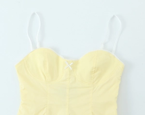 Dettaglio del top in popeline giallo tenue con spalline in pizzo e piccolo fiocco