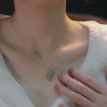 Dettaglio di una collana vintage dorata con pendente in pietra verde indossata da modella