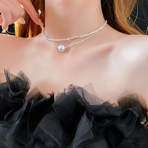 Détail d'un collier argenté à deux rangs avec perle blanche porté par un mannequin