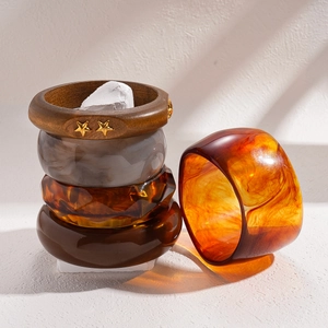 Retro resin and wood bangle set with amber texture and gold star accents on stone