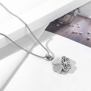 Macro detail of silver four-leaf clover pendant with pavé diamonds on a gift box lid