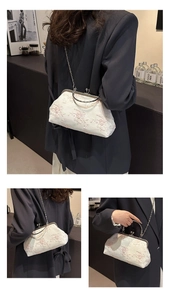 Detail view of a white lace evening bag with floral embroidery and metal clasp