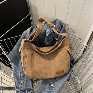 Dettaglio della borsa a tracolla in velluto a coste kaki posta in un cesto con stile casual