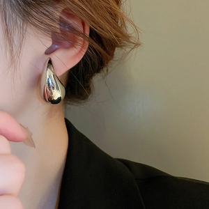 Close-up of a sleek silver teardrop earring featuring a high-polish metallic finish