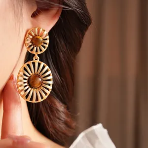 Vintage tiger eye oval earrings with gold metal radial texture on a female model