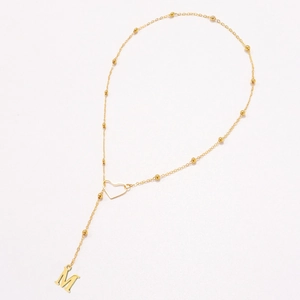 Detailed close-up of golden Y-shaped necklace with hollow heart and M letter pendant
