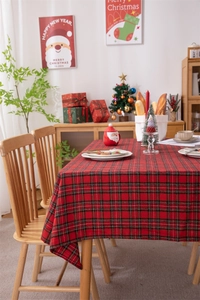 Close-up of festive red and black plaid tablecloth with gold silk details and fringe