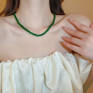 Gros plan d'un collier de perles de verre géométriques vert émeraude sur un modèle