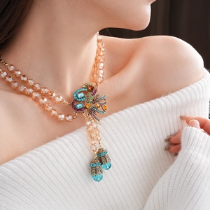 Detail of vintage peacock pendant necklace with colorful rhinestones on model