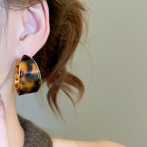 Gros plan de boucles d'oreilles créoles en résine écaille avec bordure dorée à l'or 18K