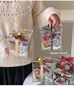 Detail of hand-held acrylic Christmas gift box with apple, cinnamon, and festive ribbons