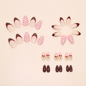 Detail of sweet cherry press-on nails with French tips and polka dot designs on beige surface
