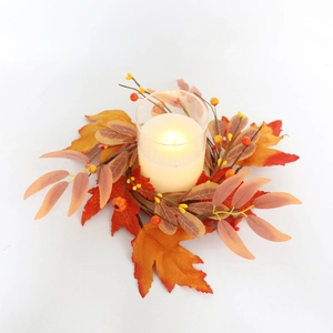 Close-up of autumn candle ring with maple leaves, berries, and a clear glass holder