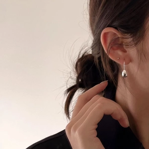 Close-up of polished 925 sterling silver water drop earrings worn by a model