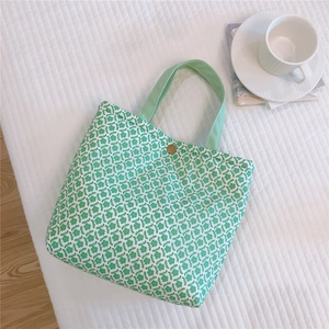 Detail of floral canvas lunch bag with green floral pattern and gold metal snap button