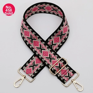 Close-up of pink and black geometric woven bag strap with adjustable gold metal buckles