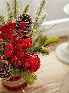 Detail of Christmas pine cone centerpiece with red berries and LED lights in plaid base