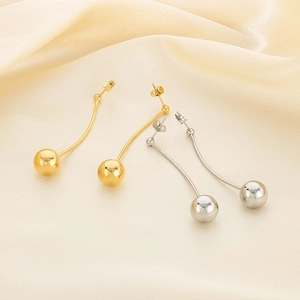 Détail du pendentif boule 12mm sur une longue boucle d'oreille dorée minimaliste