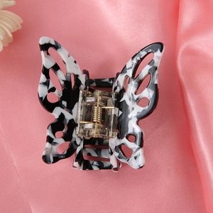 Detail of marble pattern butterfly hair claw clip with hollow design on pink silk