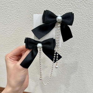 Detail of black ribbon bow hair clips with long pearl tassel chains for girls