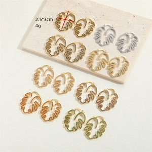 Hollow leaf earrings in multiple colors on white stone background with size indicators