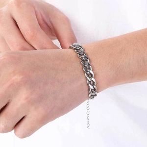 Detail of silver stainless steel Cuban chain bracelet worn on wrist with white shirt