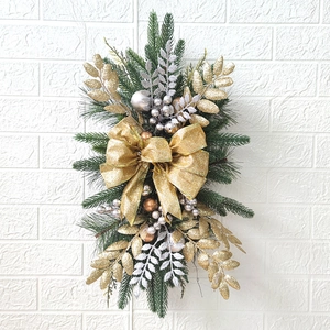 Close-up of Christmas swag with gold glitter bow and metallic ornaments on green pine needles
