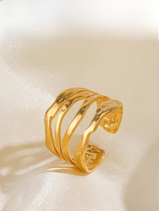 Vue détaillée d'une bague dorée ondulée avec texture martelée sur de la soie