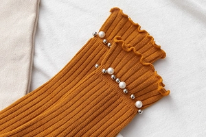 Close-up of orange crew socks with ruffle lettuce edge and pearl rivet embellishments