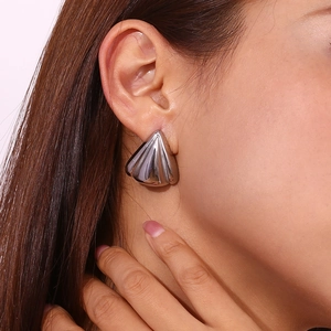 Macro shot of silver shell petal earrings showing metallic texture on ear model