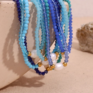 Detailed macro view of blue crystal beads and natural freshwater pearl on steel necklace