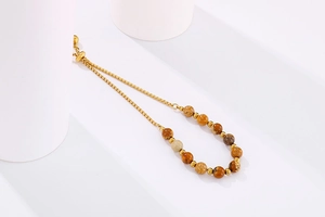 Detail of adjustable gold box chain bracelet with natural earthy stone beads