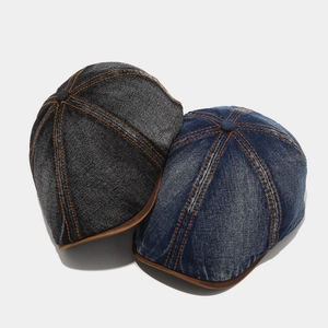 Close-up of vintage washed denim newsboy caps with orange contrast stitching and leather brim