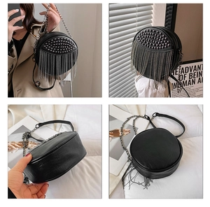 Detail view of round black crossbody bag with punk style metal rivets and chain fringe