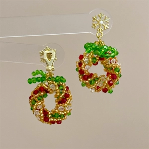 Macro detail of handmade beaded Christmas wreath earrings with gold snowflake accents