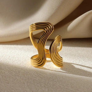 Macro shot of gold irregular wave ring with refined parallel texture and curved lines