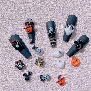 Macro shot of Halloween nail charms featuring ghosts, pumpkins, and black cats decor