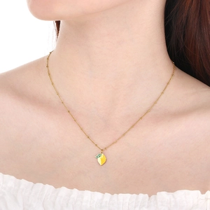 Gros plan d'un collier chaîne à perles dorées avec pendentif citron en émail sur un mannequin