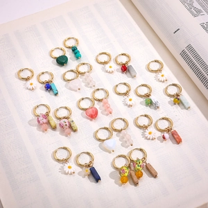 Detailed close-up of golden hoop earrings featuring blue porcelain and floral charms