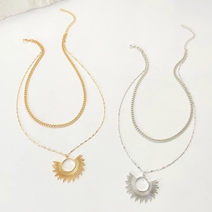 Vue détaillée des colliers double rang or et argent avec pendentif soleil sur fond blanc