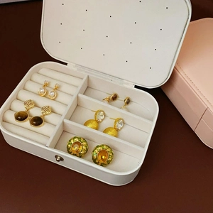Top view of white PU leather travel jewelry box with beige velvet slots for earrings