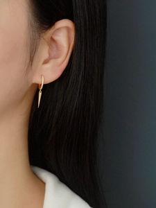 Close-up of gold vermeil spike earring with pavé-set zircons worn by a model