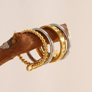 Detailed view of 18K gold and silver rings with zircon accents on natural wood branches