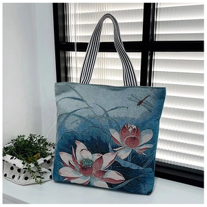 Detail of vintage navy tote bag with lotus print and striped shoulder strap by a window