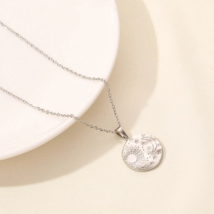 Macro detail of vintage celestial moon and star pattern on round stainless steel pendant