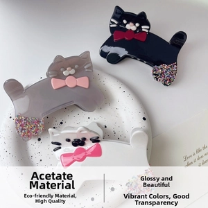 Close-up of three acetate cat-shaped hair claws with colorful bows and glitter accents