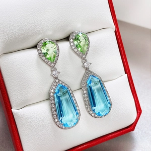 Macro shot of pear-cut blue and green zircon drop earrings with pavé diamond halo